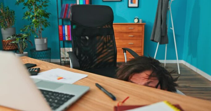 Funny, comical, man with round, thick glasses, disheveled hair, leans out from under desk in corporate office, looking at camera, blinking eyes, with silly face, nerd, meme, cabaret performer