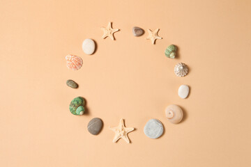 Seashells, starfish and stone in circle on brown background with space for text.