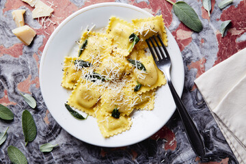 ravioli with butter parmesan and sage dish on a red marble table