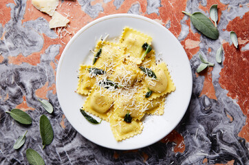 ravioli with butter parmesan and sage dish on a red marble table