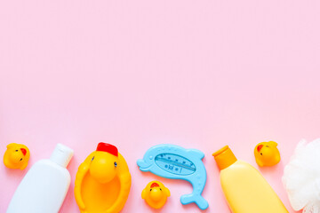 Baby bath products on a pink background. Rubber ducks, thermometer, shampoo. Flat lay, copy space
