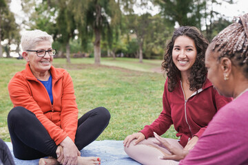 Multiracial women sitting and talking outdoor at city park - Multi generational people having fun...