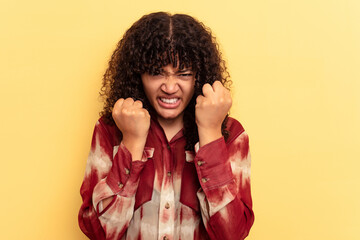 Young mixed race woman isolated on yellow background upset screaming with tense hands.