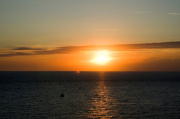 Small sailboat on the high seas at sunset.