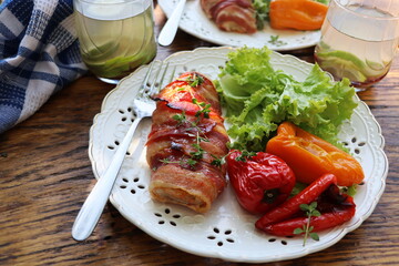 Fototapeta na wymiar Grilled chicken breast wrapped in bacon served with salad on wooden rustic table . Dinner background