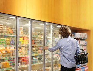  Men choosing frozen food from a supermarket freezer.