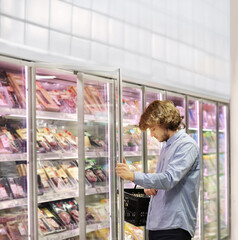 Fototapeta na wymiar Men choosing frozen food from a supermarket freezer.