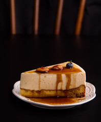 Sweet cream cheesecake dessert with caramel and nuts on a black background. Copy space