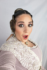 Funny portrait of fallera girl in vintage dress taking a selfie with surprised face