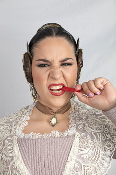 Caucasian girl dressed as fallera eating licorice or Glycyrrhiza glabra looking at camera