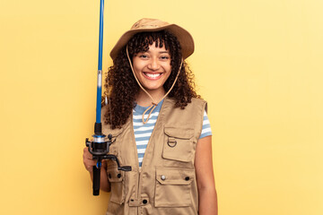 Fototapeta premium Young mixed race fisherwoman holding a rod isolated on yellow background