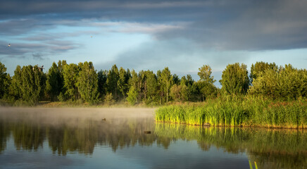 Summer dawn on the Ural lake with fog, Russia
