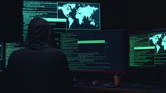 Back View Of Male Hacker Hacking With Code On Multiple Computer
