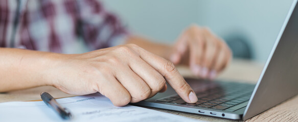 Cropped close-up image of a businessman`s hands typing working on a laptop at the home office. Freelancer, remote occupation, tutor, student e-learning concept