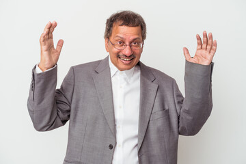 Middle aged indian business man isolated on white background receiving a pleasant surprise, excited and raising hands.
