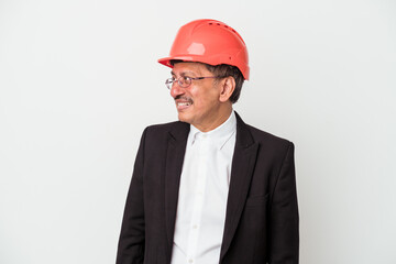 Middle aged indian architect man isolated on white background looks aside smiling, cheerful and pleasant.