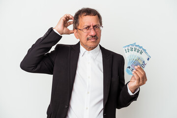 Middle aged indian business man holding bills isolated on white background being shocked, she has remembered important meeting.