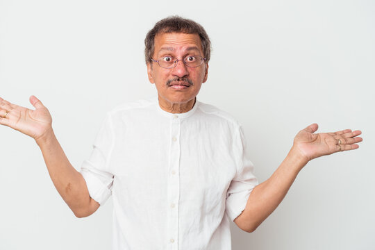 Middle aged indian man isolated on white background confused and doubtful shrugging shoulders to hold a copy space.