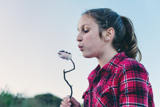 teen girl toasting marshmallows on a camping holiday