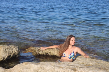 Fototapeta na wymiar Young brunette girl on rocks beach in Malta, untouched nature