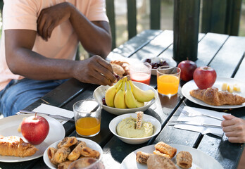 Hand of an African man picking fruit from the table where they are having breakfast.