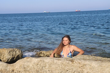 Young brunette girl on rocks beach in Malta, untouched nature
