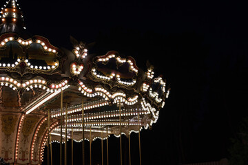 Vintage carousel lights in the park, retro merry-go-round on a summer evening. © Natalia