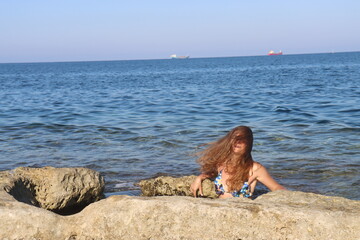 Young brunette girl on rocks beach in Malta, untouched nature