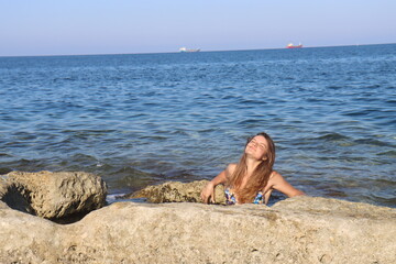Fototapeta na wymiar Young brunette girl on rocks beach in Malta, untouched nature