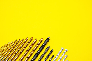 Set of drills for wood, metal and concrete on a yellow background.