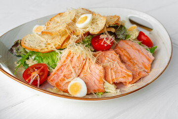Caesar salad with grilled chicken on white wooden background