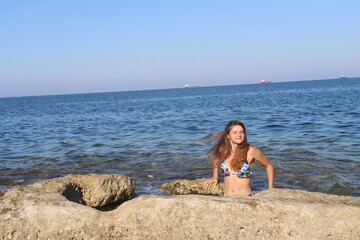 Young brunette girl on rocks beach in Malta, untouched nature