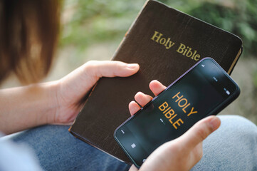 Women holding mobile phone praying worship to God with church online with the bible.Quarantine from...