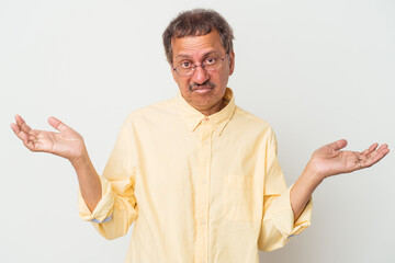 Middle aged indian man isolated on white background doubting and shrugging shoulders in questioning gesture.