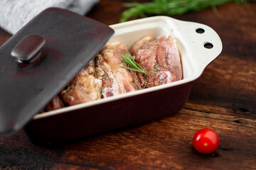 Raw chicken thighs in a baking dish on a wooden background. Preparation for baking.