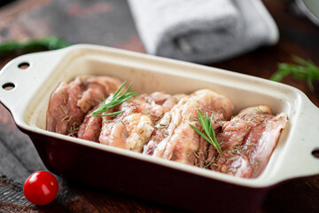 Raw chicken thighs in a baking dish on a wooden background. Preparation for baking.