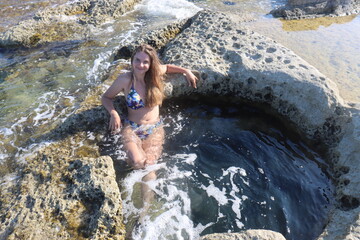 Young brunette girl on rocks beach in Malta, untouched nature