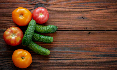 Fresh cucumbers and tomatoes on a wooden background.