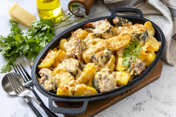 Baked mackerel with potatoes and cheese on a marble tabletop.