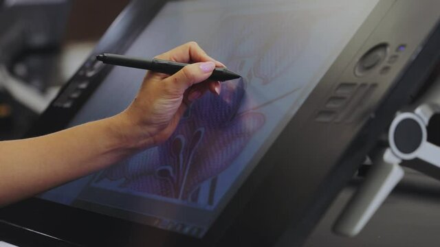 The designer draws on a graphics tablet. Working with interactive pen display. Drawing on a graphics tablet. closeup. Wallpaper production.