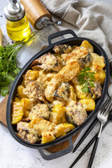Baked mackerel with potatoes and cheese on a marble tabletop.