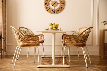 Stylish white dining table and wicker chairs in room. Interior design