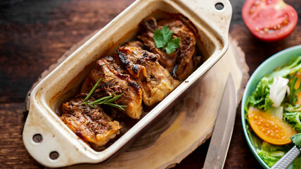 Baked fried chicken thighs in a baking dish on a wooden background.