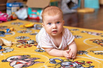 A small child on a rug among toys