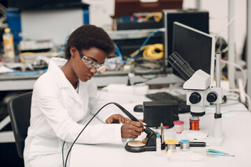 Scientist african american woman working in laboratory with soldering iron