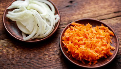 Sliced onions and carrots on a dark wooden background. Ingredients, preparation for cooking.