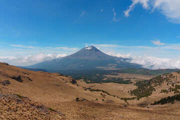 Fototapeta na wymiar The Popocatepetl volcano with a rocky hill in the foreground