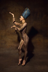 Portrait of young woman in image of Nefertiti in art performance isolated on brown vintage...