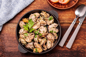 Peeled mussels in sauce on a dark wooden background.