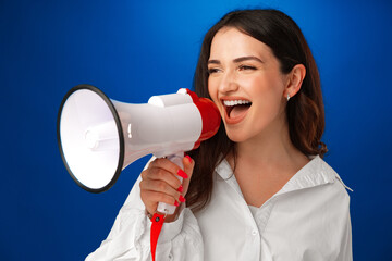 Young brunette businesswoman holding a megaphone against blue background